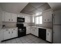 Efficient kitchen with white cabinetry, tile flooring, black appliances, and a window for natural light at 3467 Garden East Dr, Las Vegas, NV 89121