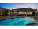 Resort-style backyard featuring a covered patio, outdoor seating and a sparkling swimming pool with custom rock features at 3837 Genoa Dr, Las Vegas, NV 89141