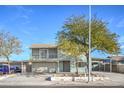 Two-story home features a two-car garage, balcony, and a lush, mature tree in the front yard at 401 Altamira Rd, Las Vegas, NV 89145