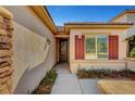 Inviting front entrance with custom ironwork door and colorful red window shutters with well maintained landscaping at 4593 Weitzman Pl, Las Vegas, NV 89141