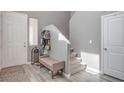 A bright entryway with neutral walls, gray floors, a bench, coat rack, and access to the staircase at 6904 Baylor Creek St, North Las Vegas, NV 89086