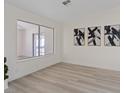 Bright living room with large window, modern artwork, and light wood-look flooring at 7138 Sixshooter Dr, Las Vegas, NV 89119