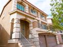 A low angle view of this two-story home, featuring a front porch and two-car garage at 9739 Fox Estate St, Las Vegas, NV 89141