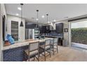 Modern kitchen with stainless appliances, dark cabinets, and breakfast bar with seating at 11283 Gravitation Dr, Las Vegas, NV 89135