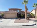 Inviting two-story home featuring desert landscaping, a two-car garage, and shade from mature palm trees at 1893 Donnington Ct, Las Vegas, NV 89123