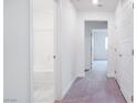 Hallway with white walls and doors leading to bathroom and bedroom with neutral color palette and carpeted floors at 3542 Arcadian King Ave, Las Vegas, NV 89106