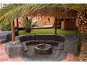 Outdoor firepit area with custom stone seating, tiki torches, and lush backyard setting at 4745 Gunlock Cir, North Las Vegas, NV 89031