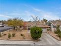 Inviting single-story home with mature trees, xeriscaping, a brick chimney, and a two-car garage at 6858 Groveview Ln, Las Vegas, NV 89103