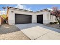 Spacious three-car garage featuring a paved driveway and low-maintenance desert landscaping around the perimeter of the home at 9359 Brownstone Ledge Ave, Las Vegas, NV 89149