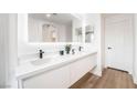 Bathroom features a double sink, modern fixtures, large mirror, and wood-look floors at 10809 Garden Mist Dr # 2072, Las Vegas, NV 89135