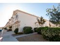Exterior side view of condominium showing garage entrances, sidewalk and bushes at 8628 Tomnitz Ave # 101, Las Vegas, NV 89178