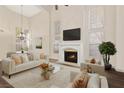 Bright living room featuring vaulted ceilings, a fireplace, and lots of natural light from large windows at 9517 Spanish Steps Ln, Las Vegas, NV 89117