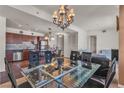 Open dining area with a modern glass table, chandelier, and an adjacent kitchen at 2405 W Serene Ave # 817, Las Vegas, NV 89123