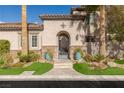 Beautiful home featuring an iron front door, arched entrance, manicured lawn, and palm trees at 2436 Grassy Spring Pl, Las Vegas, NV 89135