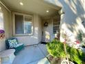 Inviting front porch with a cozy chair, side table and potted plants creating a welcoming entrance at 4534 Regalo Bello St, Las Vegas, NV 89135