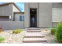 Inviting front entrance with stone steps and desert landscaping, leading to a secure front door at 6630 Windy Palm St, North Las Vegas, NV 89086