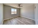 Neutral bedroom features wood-look floors, a ceiling fan, and a bright window at 6631 S Parkwood Ct, Pahrump, NV 89061