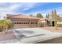 Charming single-story home with a red-tiled roof, desert landscaping, and an attached three-car garage at 1202 Healing Waters Ln, North Las Vegas, NV 89031