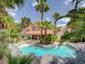 Serene backyard oasis with a sparkling pool, lush landscaping, and plenty of privacy at 8324 Slate Harbor Cir, Las Vegas, NV 89128