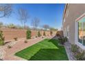 Landscaped backyard featuring synthetic grass and desert landscaping at 9853 Russian Hill St, Las Vegas, NV 89141