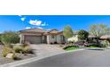 Inviting single-story home with a three-car garage, xeriscaping, and green lawn at 33 Hassayampa Trl, Henderson, NV 89052