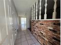 Foyer with gray tile flooring, a white door with silver hardware, a brick accent wall and white railing at 4013 El Camino Ave, Las Vegas, NV 89102
