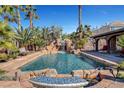 Inviting backyard pool with rock waterfall, mature landscaping and a built-in table with seating at 563 Moon Chase St, Las Vegas, NV 89110