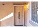 Charming front door with a 'Welcome' sign, complemented by a warm exterior light fixture and a view of the window at 6680 Abruzzi Dr # 102, North Las Vegas, NV 89084
