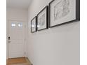 Bright hallway featuring modern artwork, a white front door with glass panes, and neutral flooring at 1876 Jamie Brook Pl, North Las Vegas, NV 89084