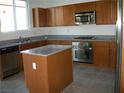 Bright kitchen with stainless steel appliances, a kitchen island, and wooden cabinets at 3104 Naggio Shores Ave, Las Vegas, NV 89141