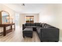 Bright living room featuring a comfortable gray sectional sofa, wood-look flooring, and access to a balcony at 3151 Soaring Gulls Dr # 1049, Las Vegas, NV 89128