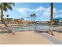 Community pool with beach-like entry, lounge chairs, shade structures and palm trees under bright blue sky at 3151 Soaring Gulls Dr # 2113, Las Vegas, NV 89128