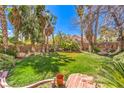 Lush backyard with mature palm trees, green grass, and rock landscaping features at 7211 Galley Dr, Las Vegas, NV 89147