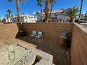 A brick-walled patio with two chairs on a gravel surface, surrounded by palm trees at 8160 Autumn Star Ave, Las Vegas, NV 89145