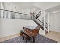 Grand foyer with a beautiful piano, staircase with black railing, and tiled flooring at 8426 Sluman Ct, Las Vegas, NV 89128