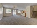 Open-concept living room with neutral carpet, lots of windows, and view to kitchen and backyard at 8980 High Horizon Ave, Las Vegas, NV 89149