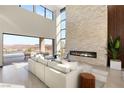 Bright living room featuring a stone fireplace, soaring windows, modern furniture and seamless indoor-outdoor living at 10 Sand Star Ln, Henderson, NV 89011