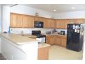Bright kitchen featuring wood cabinets, black appliances, and a breakfast bar at 2679 Lochleven Way, Henderson, NV 89044