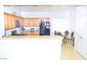 Bright kitchen featuring wood cabinets, black appliances, and a cozy dining area with a glass-top table at 2679 Lochleven Way, Henderson, NV 89044