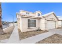 Side view of charming two-story home featuring a two-car garage and a low-maintenance front yard at 3425 Golden Sage Dr, North Las Vegas, NV 89032
