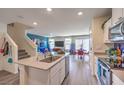 Open-concept kitchen featuring island with sink, white cabinets, and seamless transition to the dining and living areas at 4806 Lilac Ridge Ave # 31, Las Vegas, NV 89141