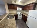 Condo kitchen featuring granite countertops, white appliances, and dark cabinets at 6800 E Lake Mead Blvd # 1018, Las Vegas, NV 89156