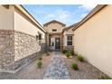 Paver walkway leads to the covered front porch with stone accents and modern front door at 8575 Nicholas James Ave, Las Vegas, NV 89143