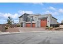 Modern home exterior with three-car garage, desert landscaping, and a sleek gray facade at 8591 Cloudy Dawn Way, Las Vegas, NV 89113