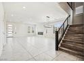 Bright living room with tile floors, modern fireplace, and staircase with black metal railing at 8591 Cloudy Dawn Way, Las Vegas, NV 89113
