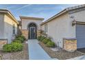 Close-up of the front entrance with an iron gate and desert landscaping at 10235 Tresor Ct, Las Vegas, NV 89135