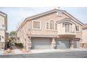 Two-story townhome featuring a three-car garage and a neutral color scheme with decorative stone accents on the facade at 10643 Petricola St # 103, Las Vegas, NV 89183