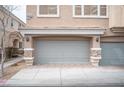 View of the two-car garage featuring stone pillars and modern gray doors, enhancing the townhome's curb appeal at 10643 Petricola St # 103, Las Vegas, NV 89183