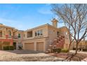 Condo exterior featuring a stucco facade, brick accents, attached garages, and tidy landscaping at 10730 Amber Ridge Dr # 205, Las Vegas, NV 89144