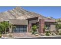 Contemporary home showcasing desert landscaping, brick driveway, and a modern glass garage door at 11185 Black Fire Opal Dr, Las Vegas, NV 89138